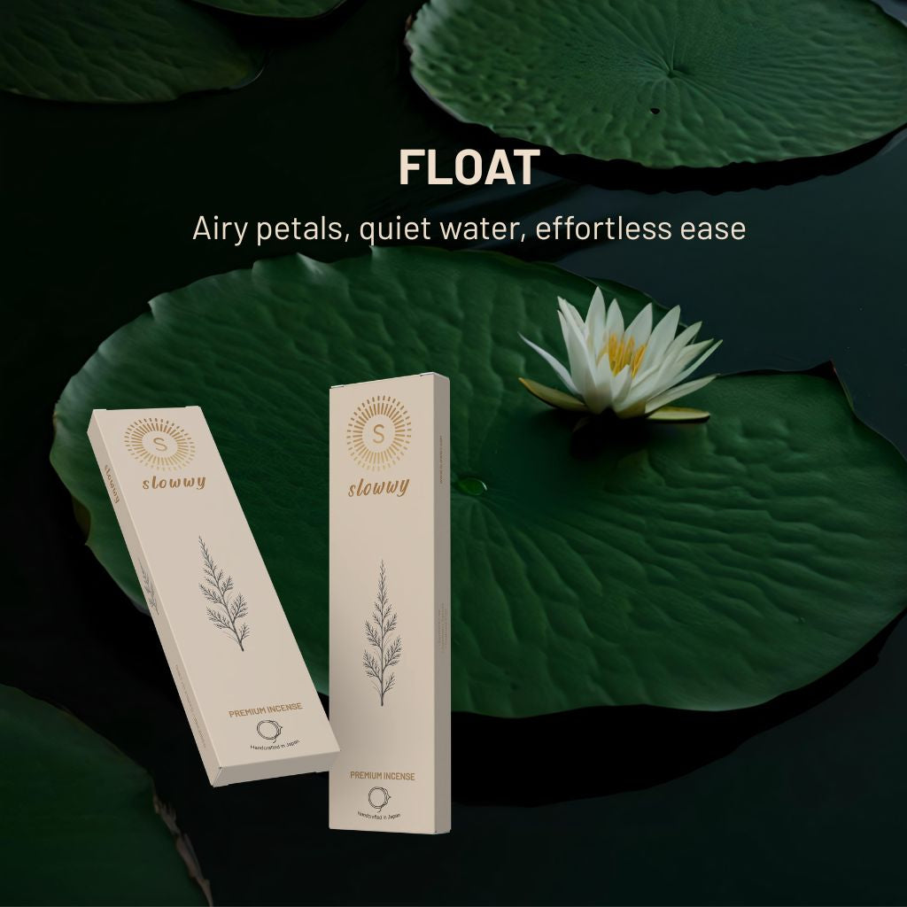 Two cream-colored slowwy brand product boxes are displayed on a dark water background with large green lily pads and a white water lily flower. White text at the top reads 'FLOAT' and 'Airy petals, quiet water, effortless ease'.