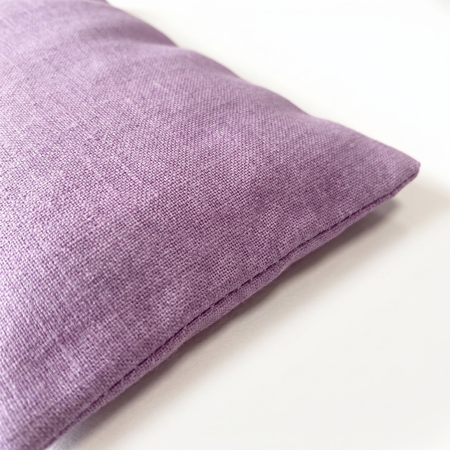 A close-up of a lavender purple textured fabric throw pillow on a clean white background.